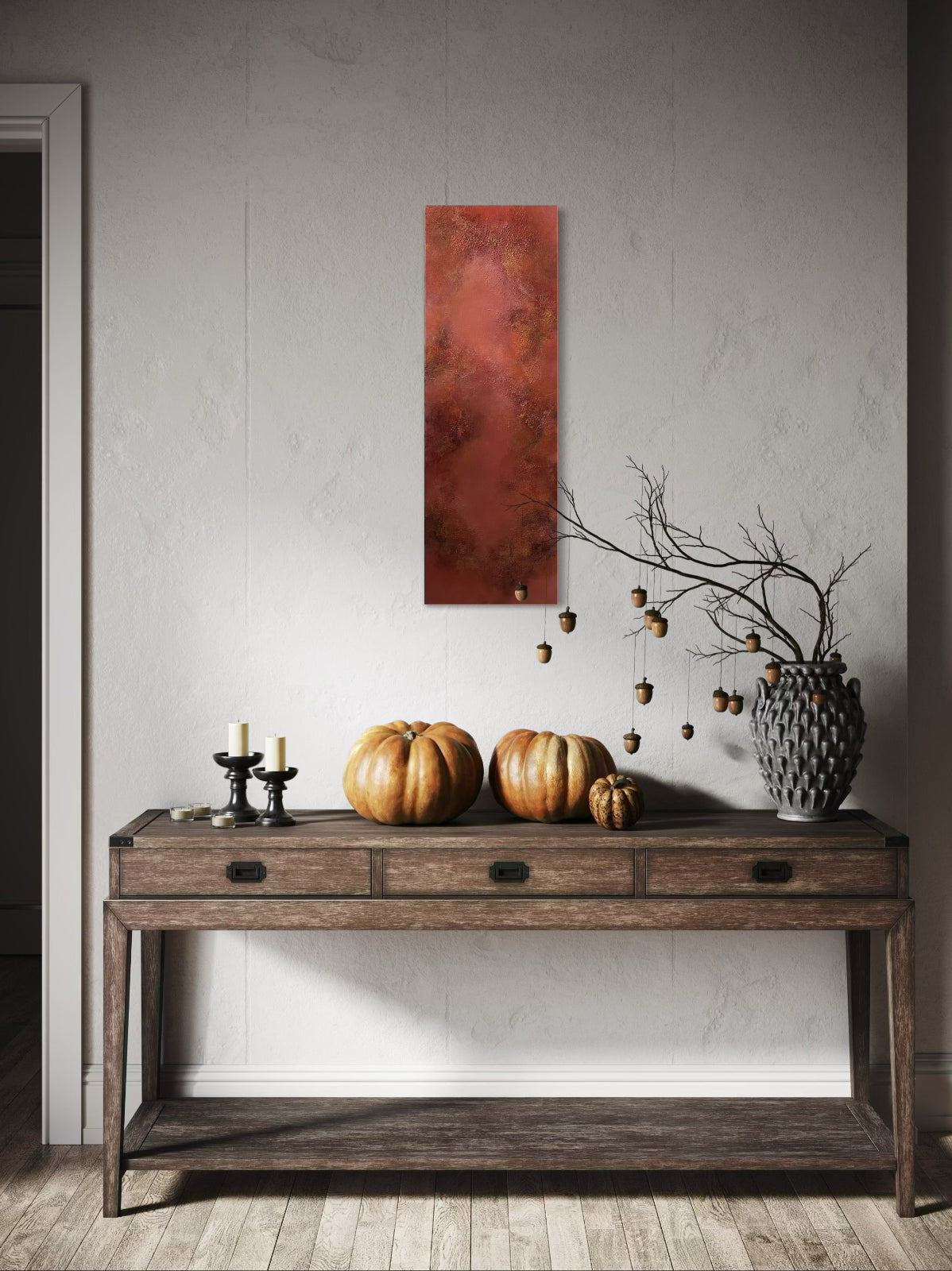 Wooden console table with pumpkins, candles, and a vase against a gray wall with a red abstract painting.
