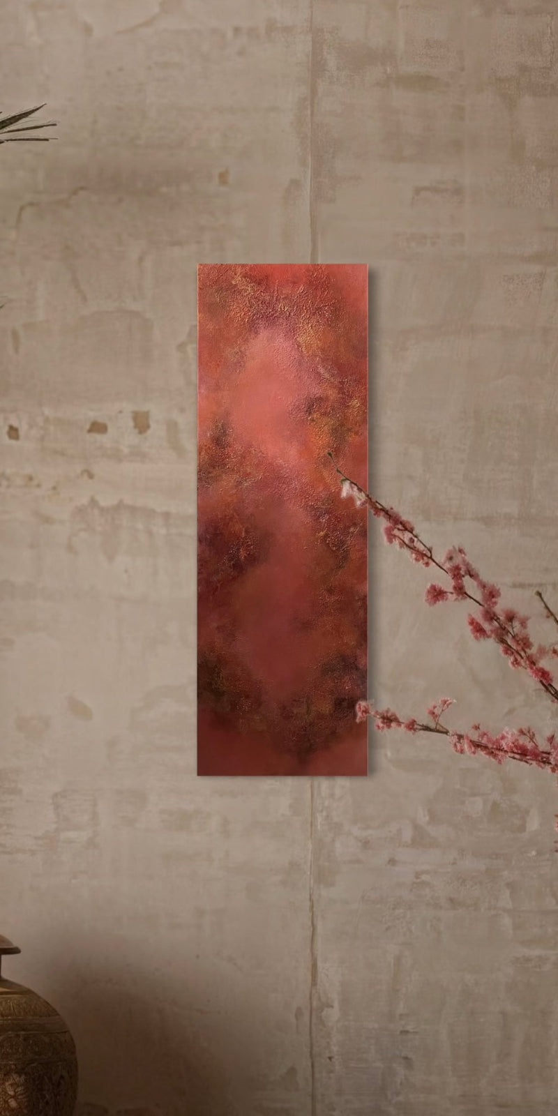 Rectangular red painting on a textured wall with a branch in the foreground
